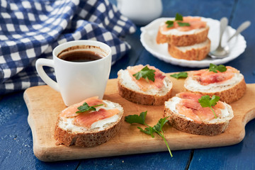 Smoked salmon and cream cheese sandwich and a Cup of coffee . On a blue background