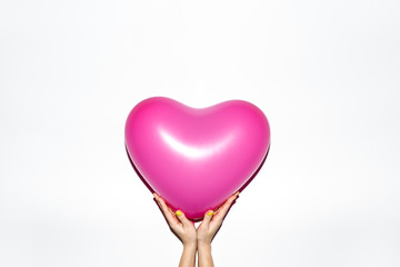 Hands holding pink heart shaped balloon on white background