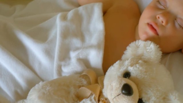 Close-up portrait of a sleeping baby in white bed