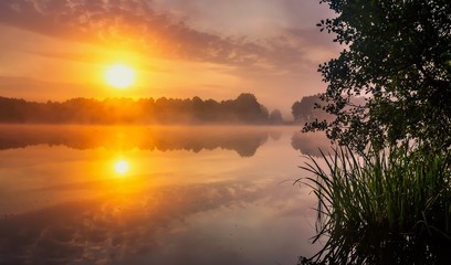 Beautiful sunrise over foggy springtime lake