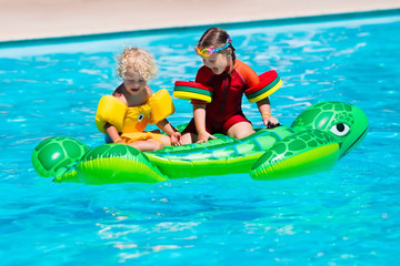 Fototapeta na wymiar Kids in swimming pool with inflatable toy