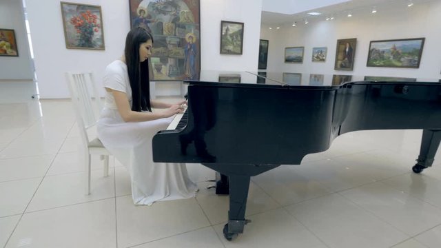 Musical pianist playing classical grand piano in a center of concert hall. 4K.