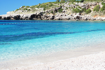 Blue clear water on the beach with a rock