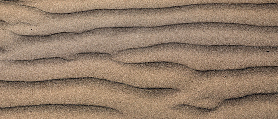 Fototapeta na wymiar Waves of sand on the beach high contrast color gradient, background