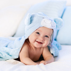 Baby in towel after bath in bed