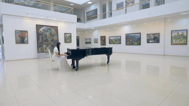 Graceful woman pianist playing piano in opera hall. 4K.