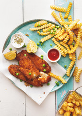 Fish and chips served with sauces and peas