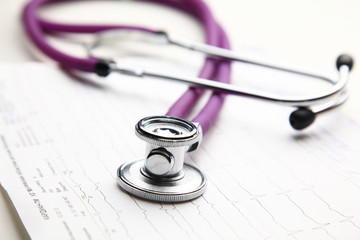 Stethoscope with cardiogram lying on desk in hospital