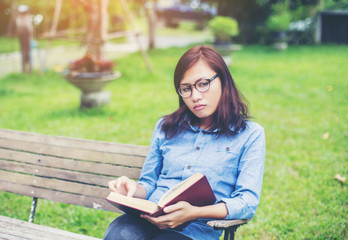 Obraz premium Hipster charming girl relaxing in the park while read book, Enjo