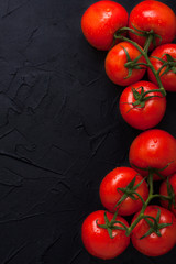 Red fresh organic tomatoes on black concrete background