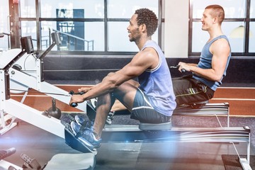 Muscular men using rowing machine