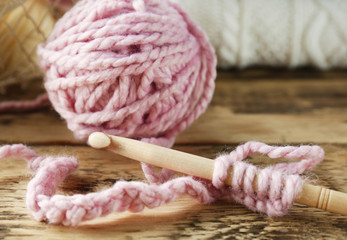 Fototapeta na wymiar Pink ball of knitting yarn and hook on wooden table