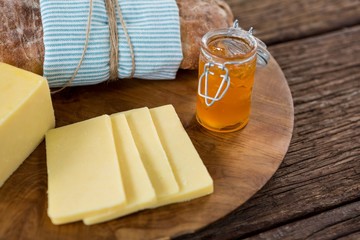 Slices of cheese, bread and fruit jam on wooden board