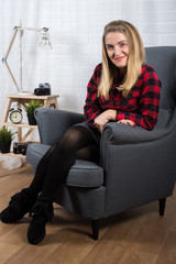 Obraz premium A beautiful young woman in a red lumberjack shirt sits on a chair