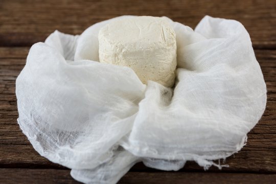 Cottage cheese in white cloth on wooden board