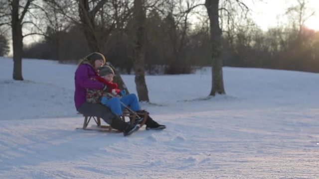 Winter happy family - mother sledding with child in winter park