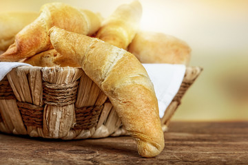 Crispy fresh croissants in a basket on a wooden table