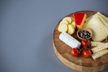 Variety of cheese with cherry tomato and spices on wooden board