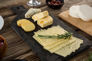 Variety of cheese and rosemary herbs on wooden table