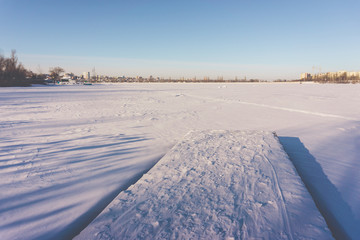 Pier in the snow and a frozen lake in the snow. Sunny winter day