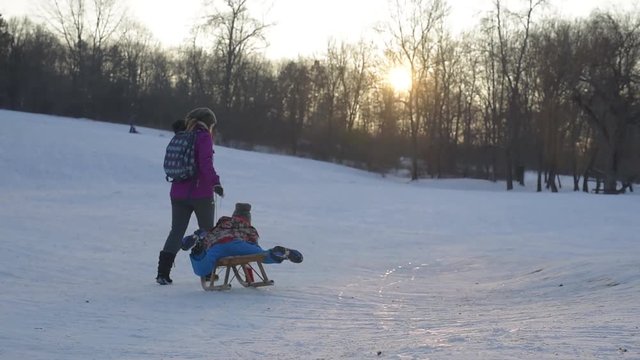  Mother is pulling a sledge with his son