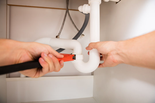 Close-up Of Plumber Fixing Sink Pipe