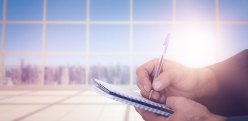 Composite image of close up of man writing in spiral book