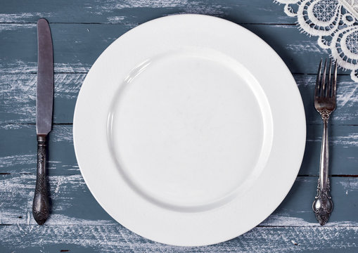 Empty white plate with knife and fork
