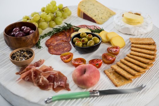 Variety of cheese with grapes, olives, salami