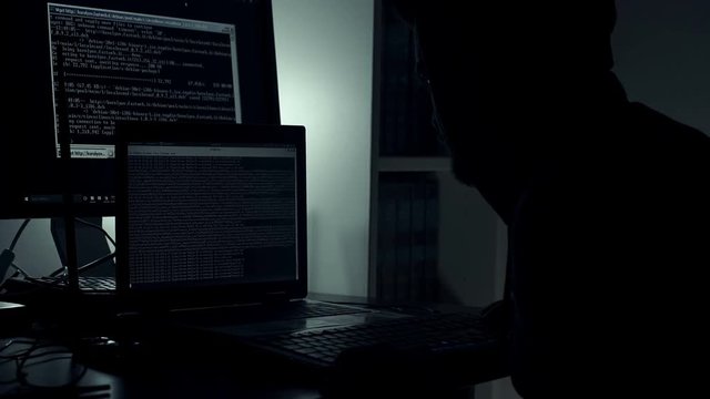 Hackers hiding in the dark manipulates a computer in the office