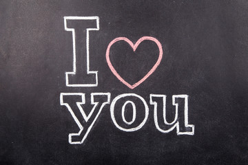 Black chalkboard with text I love you and chalks
