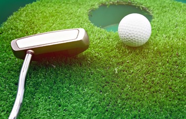 Golf ball and putter near to hole