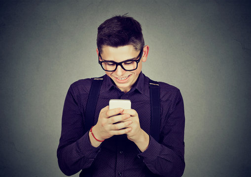 Smiling young man text messaging on mobile phone