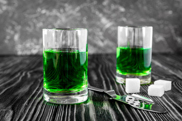 absinthe with sugar cubes and spoon on wooden background