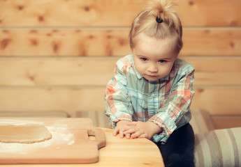 cute child in checkered shirt cooking with dough and flour