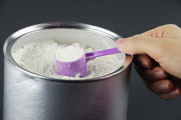 close up on hand holding scoop with baby formula