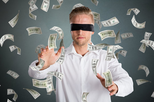 Blindfolded Businessman With Falling Money