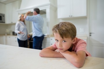 Sad boy listening to his parents arguing