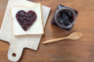 Toast with jam in shape of hearts on wooden background. Top view
