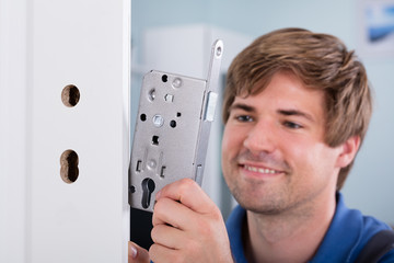 Man's Hand Installing Door Lock In Door