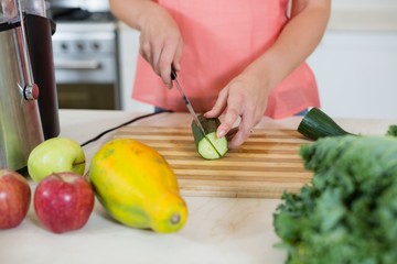 Woman cutting a cucumber on chopping board
