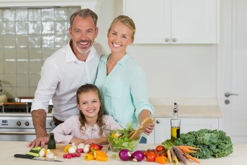 parents and daughter preparing vegetable salad 