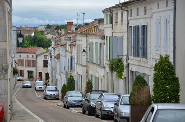 Narrow, one-way street in France with beautiful street lamps and colorful shutters