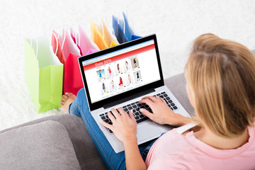 Young Woman Sitting On Sofa Using Laptop