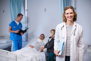 Portrait of smiling doctor standing with clipboard