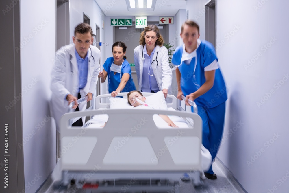 Sticker Doctors pushing emergency stretcher bed in corridor