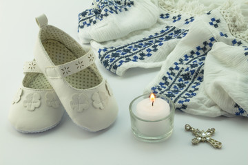 Baptism dress, booties , cross and candle on white background