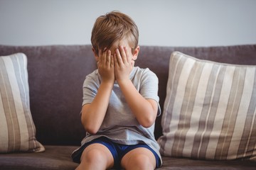 Obraz premium Upset boy sitting on sofa in corridor