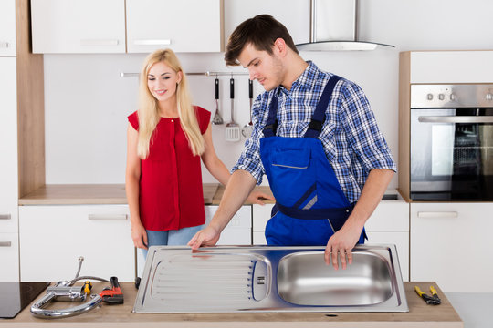 Male Plumber Fixing Stainless Steel Sink In Kitchen