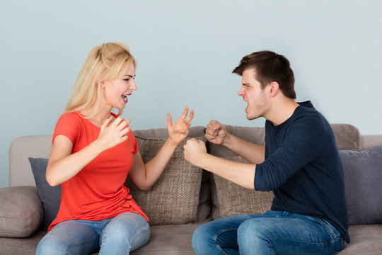 Couple Sitting On Couch Quarreling With Each Other